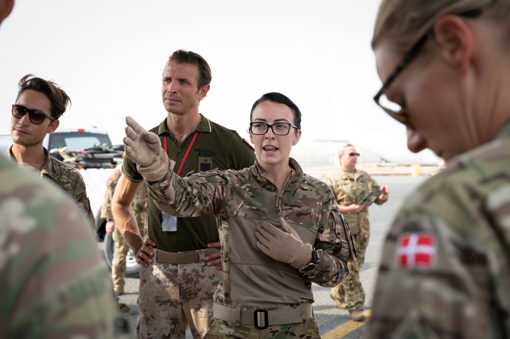 U.S. Air Force Maj. Amanda Peterson, 405th Expeditionary Aeromedical Evacuation Squadron flight nurse, briefs Danish, Italian and Canadian coalition partners on how to configure and transport patients on U.S. Air Force aircraft at the flightline on Ali Al Salem Air Base, Kuwait, July 29, 2022. Coalition partners were able to learn and share tactics and techniques with each other so in an emergency response situation, the 405th EAES and  coalition partners would be able to operate with the strength and coordination of one team. This image was altered to remove a security item. (U.S. Air Force photo by Staff Sgt. Dalton Williams)