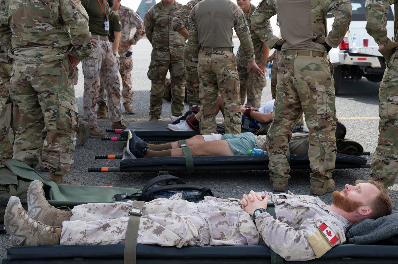 Capt. Stefan Sabo-Walsh, an infantry officer in the Canadian Armed Forces, assists the coalition forces training exercise as a mock patient to be treated by the 405th Expeditionary Aeromedical Evacuation Squadron at Ali Al Salem Air Base, Kuwait, July 29, 2022. Coalition partners were able to learn and share tactics and techniques with each other so in an emergency response situation, the 405th EAES and coalition partners would be able to operate with the strength and coordination of one team. (U.S. Air Force photo by Staff Sgt. Dalton Williams)