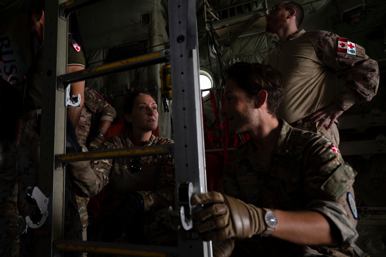 From left, U.S. Air Force Capt. Jessica Douglas, 405th Expeditionary Aeromedical Evacuation Squadron flight nurse, assists Danish, Canadian and Italian coalition partners in setting up stanchions inside a C-130J Super Hercules aircraft during a coalition training exercise at Ali Al Salem Air Base, Kuwait, July 29, 2022. These stanchions allow for patients to be stacked vertically on stretchers saving on aircraft space when needed to transport patients. (U.S. Air Force photo by Staff Sgt. Dalton Williams)
