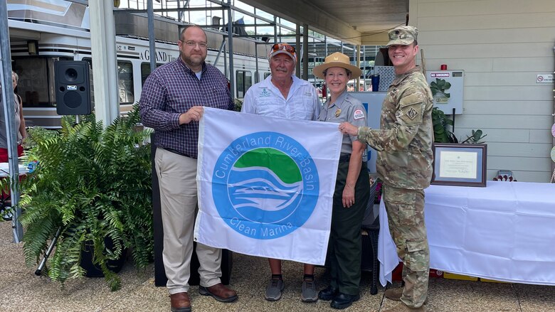 Mid-Cumberland Area Operation Manager Terrell Stoves presents Dale Hollow State Park Marina General Manager Glen Stone the Clean Marina flag, with the help of Clean Marina Coordinator and Dale Hollow Park Ranger Sondra Carmen, and Nashville District Commander Lt. Col. Joseph Sahl. The Clean Marina ceremony was held Aug. 6, 2022, at The Dale Hollow State Park Marina in Burkesville, Kentucky.