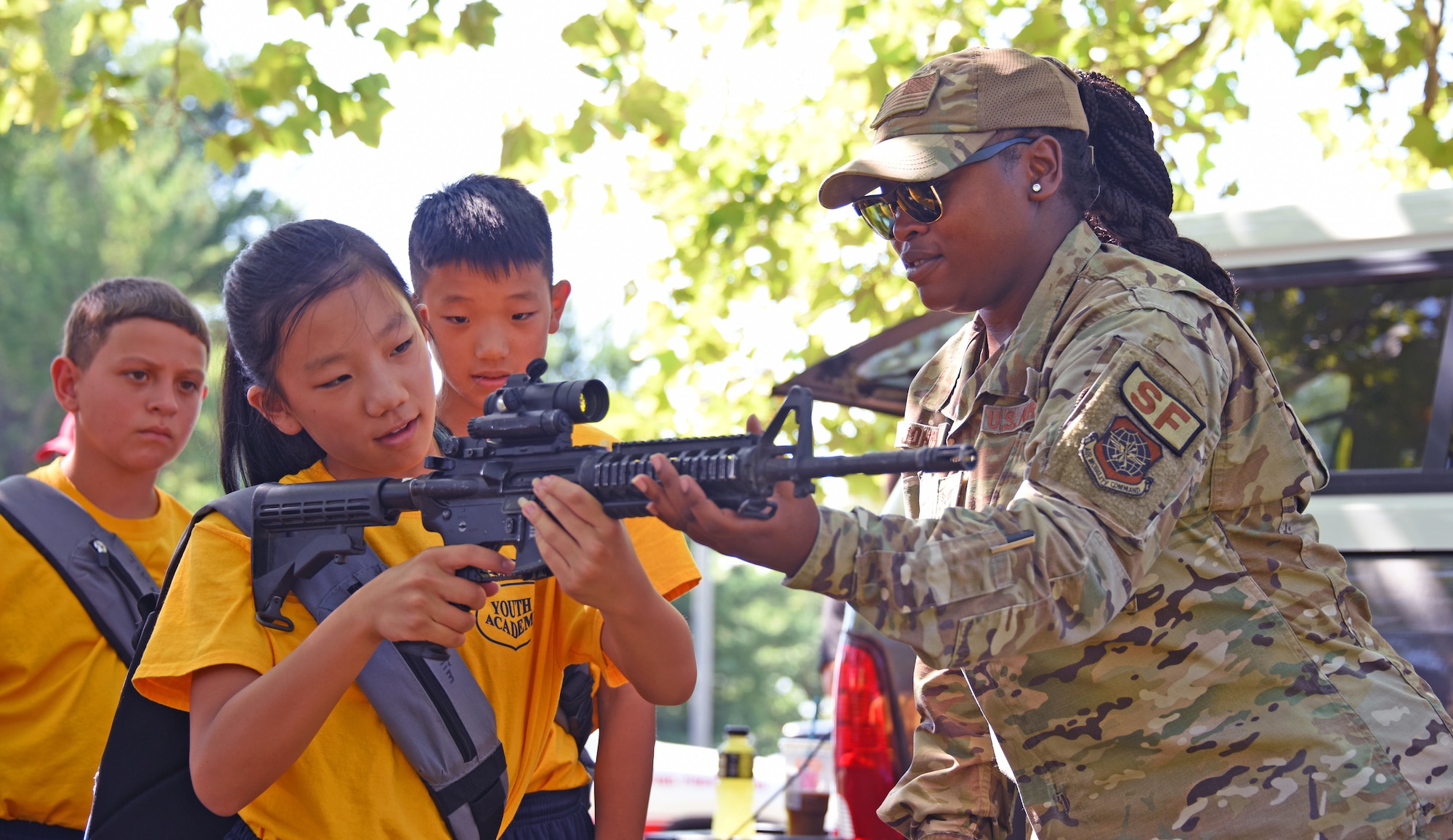 Airman trains a Youth Academy class participant on how to use a weapon.