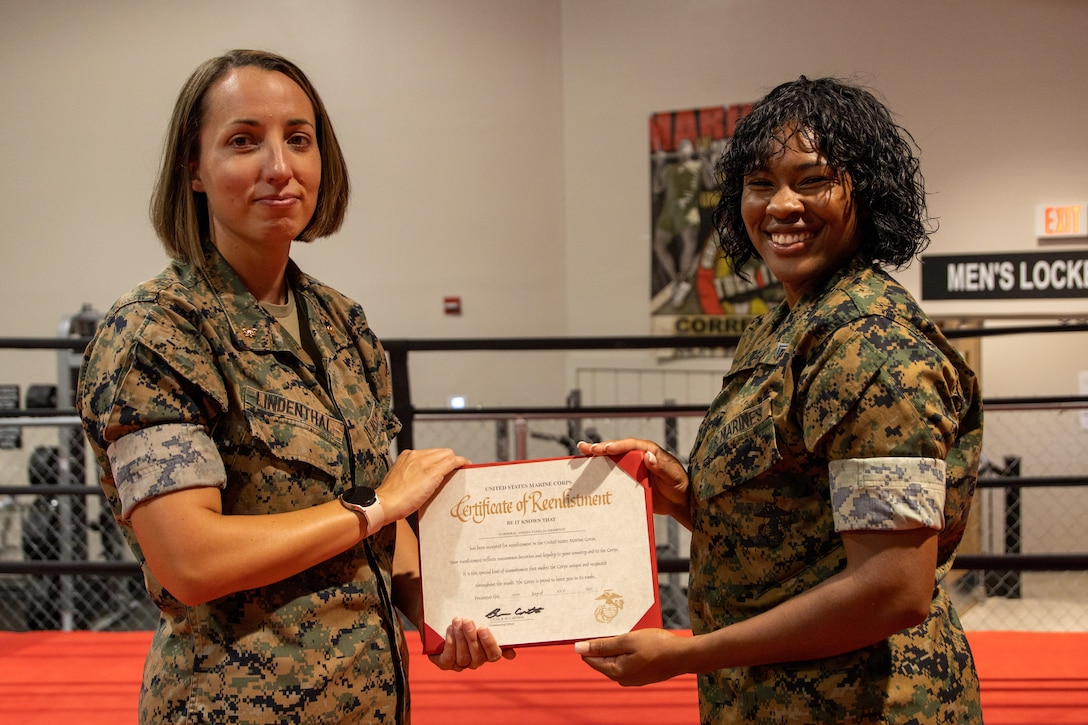U.S. Marine Corps Maj. Laura Lindenthal, an executive officer with the Personnel Administration School, Marine Corps Combat Service Support Schools Training Command, (left) and U.S. Marine Corps Cpl. Anissia Thompson, a data systems administrator with II Marine Expeditionary Force, pose for a photo during a reenlistment ceremony on Camp Lejeune, North Carolina, Aug. 8, 2022. Thompson chose to reenlist in the Camp Lejeune boxing gym to commemorate her participation on the II MEF Boxing Team during her first term of enlistment. Thompson was selected for reenlistment as part of the First Term Alignment Program which gives first term Marines the opportunity to be recommended for reenlistment and guides the Marine in making their decision to leave the Marine Corps or reenlist. (U.S. Marine Corps photo by Cpl. Eric Ramirez)