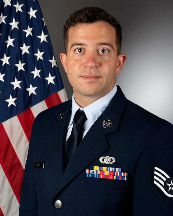 An official headshot of SSgt Gary Jones in front of the American flag. He is wearing the blue service dress uniform.
