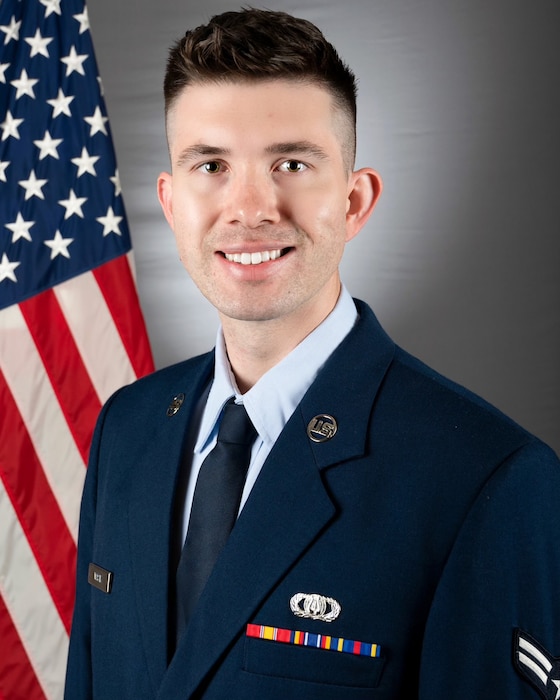 An official headshot of A1C Jeffrey Wasik in front of the American flag. He is wearing the blue service dress uniform.