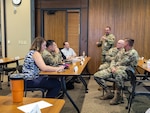 Military and civilian people are having a meeting while sitting in a roomy.