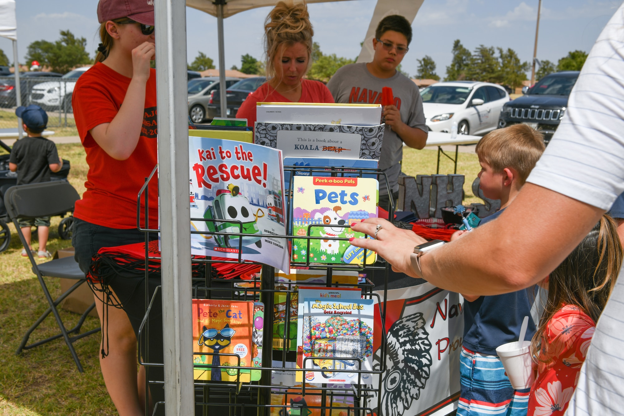 Children and parents from the 97th Air Mobility Wing examine books at the “Back to School-A-Palooza” at Altus Air Force Base, Oklahoma, Aug. 5, 2022. The event was sponsored by the 97th Force Support Squadron and other vendors both on and off base. (U.S. Air Force photo by Airman 1st Class Miyah Gray)