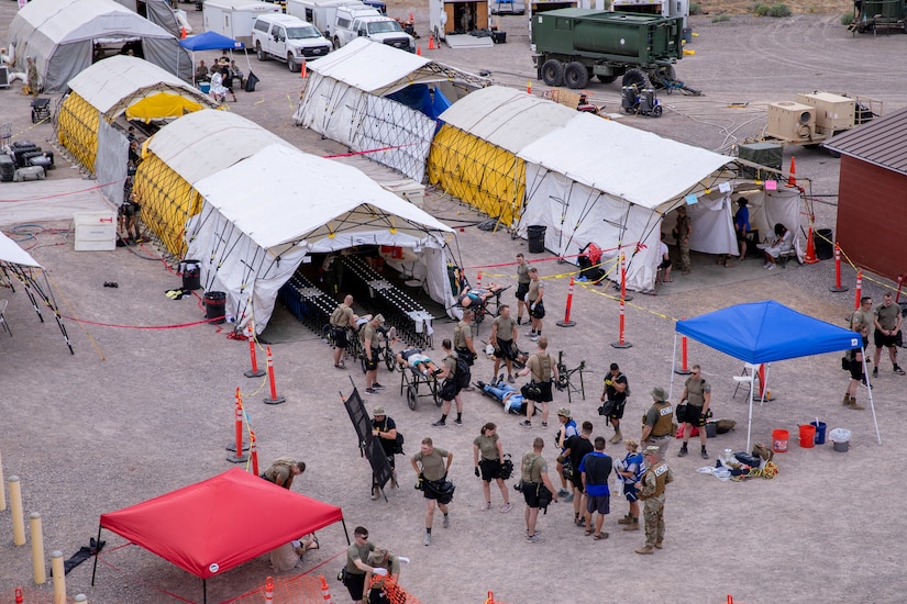 Several rescue workers and simulated casualties a re gathered around a decontamination tent