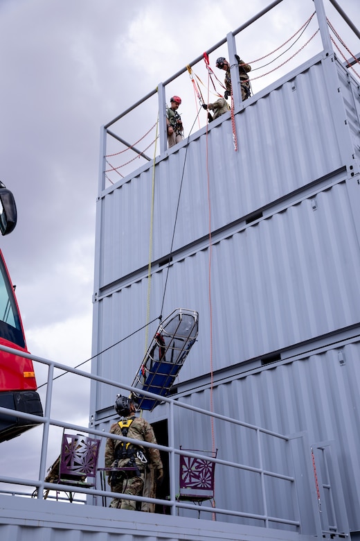 Rescue workers lower a stretcher over the side of a building