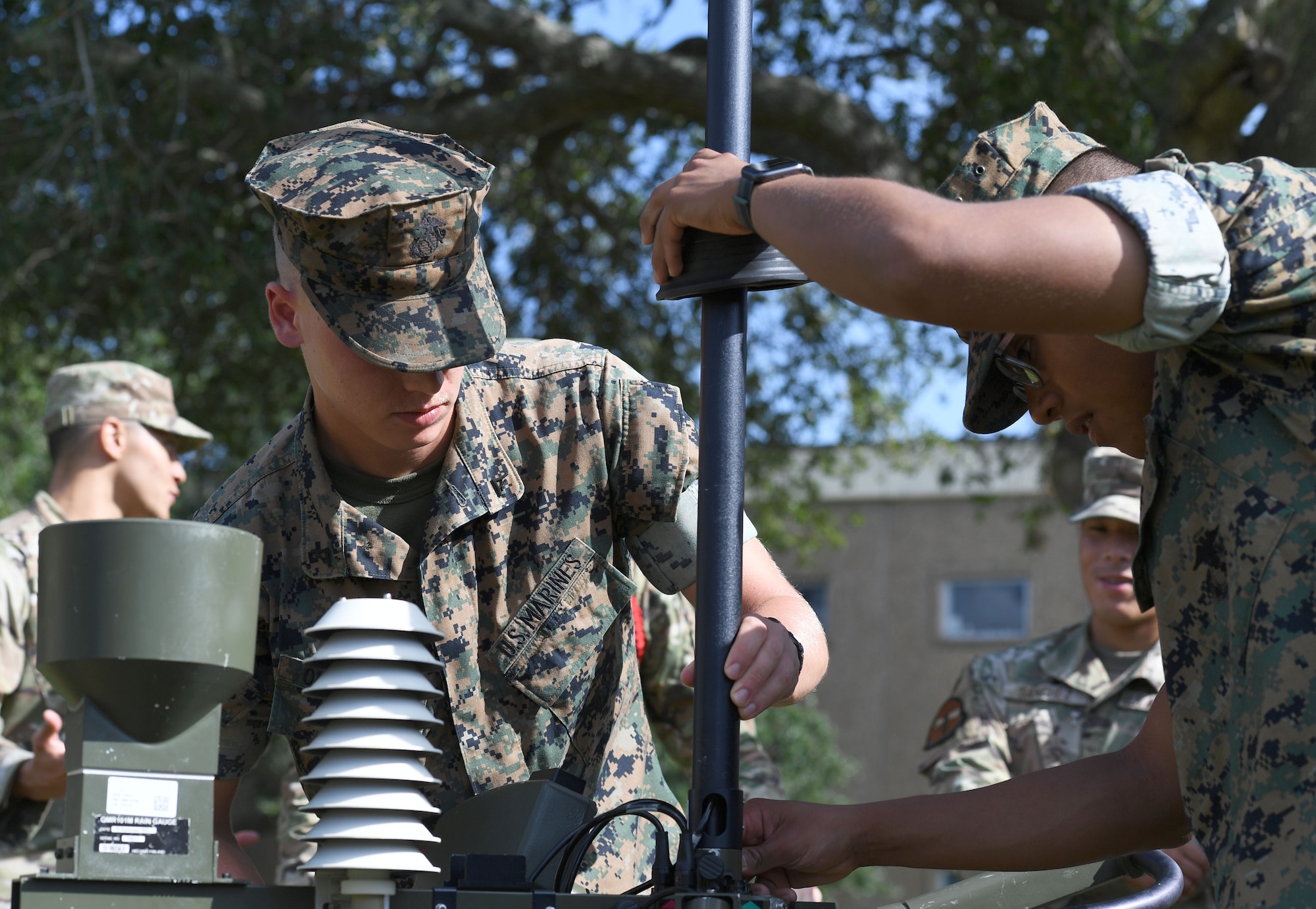 U.S. Marines Lance Cpl. Zachary Quellette and Pfc. Diego Morales Cabrera, Keesler Marine Detachment students, assemble a TMQ-53 weather sensor outside of the Joint Weather Training Facility at Keesler Air Force Base, Mississippi, July 21, 2022. The weather apprentice course, which graduated 650 students this past year, takes 151 academic days to complete. Approximately 7,400 students go through the 335th TRS's 13 Air Force Specialty Codes each year. (U.S. Air Force photo by Kemberly Groue)