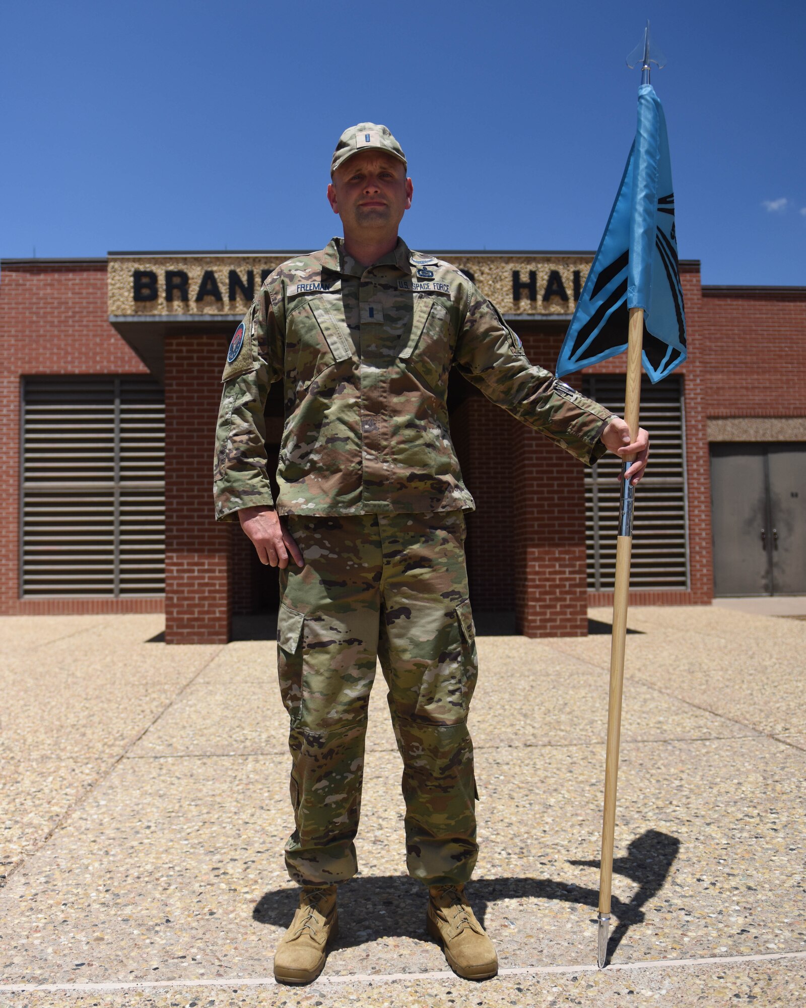 U.S. Space Force 1st Lt. Robert Freeman, 533rd Training Squadron Detachment 1 chief, holds the USSF guidon in front of Brandenburg Hall at Goodfellow Air Force Base, Texas, Aug. 2, 2022. Freeman has been stationed at Goodfellow for almost five years. (U.S. Air Force photo by Airman 1st Class Sarah Williams)