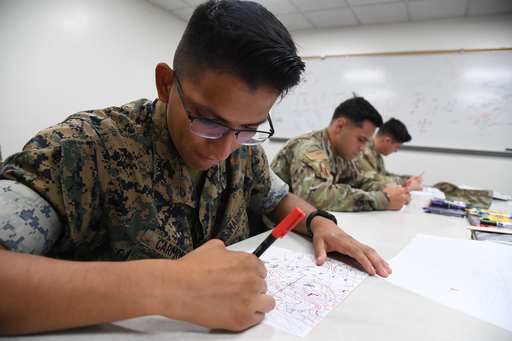 U.S. Marine Pfc. Christopher Carmona, Keesler Marine Detachment student, plots a weather chart during the weather initial skills course inside of the Joint Weather Training Facility at Keesler Air Force Base, Mississippi, July 21, 2022. The weather apprentice course, which graduated 650 students this past year, takes 151 academic days to complete. Approximately 7,400 students go through the 335th TRS's 13 Air Force Specialty Codes each year. (U.S. Air Force photo by Kemberly Groue)