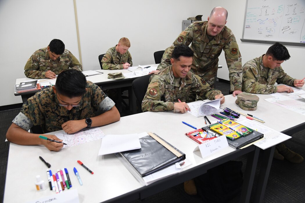 U.S. Air Force Tech. Sgt. Michael Fast, 335th Training Squadron instructor, assists students with plotting weather charts during the weather initial skills course inside of the Joint Weather Training Facility at Keesler Air Force Base, Mississippi, July 21, 2022. The weather apprentice course, which graduated 650 students this past year, takes 151 academic days to complete. Approximately 7,400 students go through the 335th TRS's 13 Air Force Specialty Codes each year. (U.S. Air Force photo by Kemberly Groue)