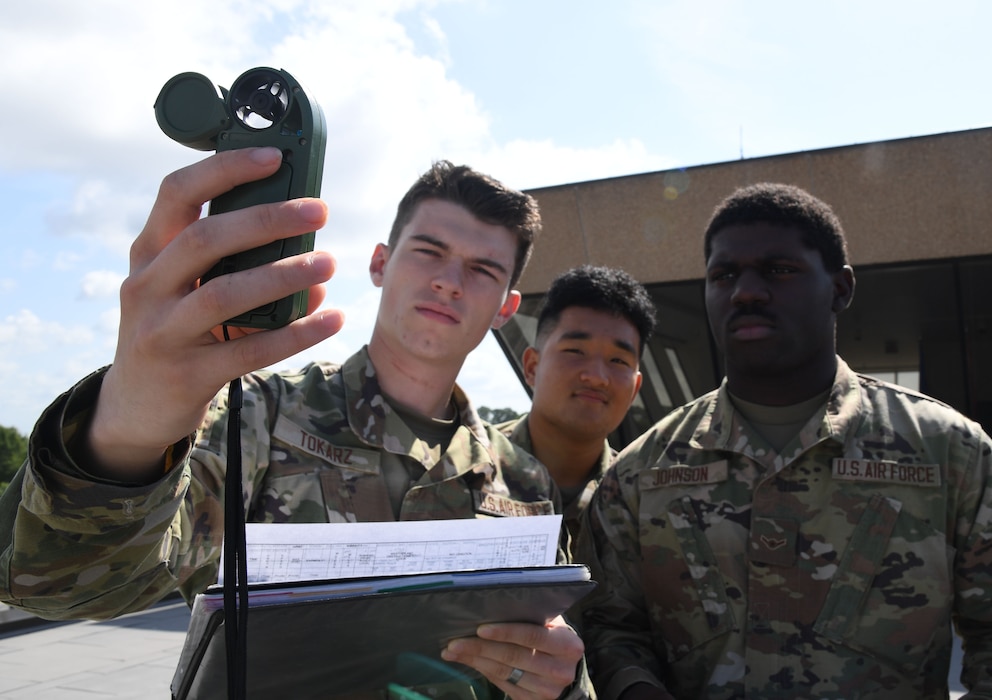 U.S. Air Force Airmen Chase Tokarz, Trey Bunao and Darrien Johnson, 335th Training Squadron students, use a handheld Kestrel weather sensor to collect weather observations during the weather initial skills course outside of the Joint Weather Training Facility at Keesler Air Force Base, Mississippi, July 21, 2022. The weather apprentice course, which graduated 650 students this past year, takes 151 academic days to complete. Approximately 7,400 students go through the 335th TRS's 13 Air Force Specialty Codes each year. (U.S. Air Force photo by Kemberly Groue)