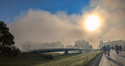 Picture of the morning sky filled with a cloud and the sunrise as the roadway descends into it.