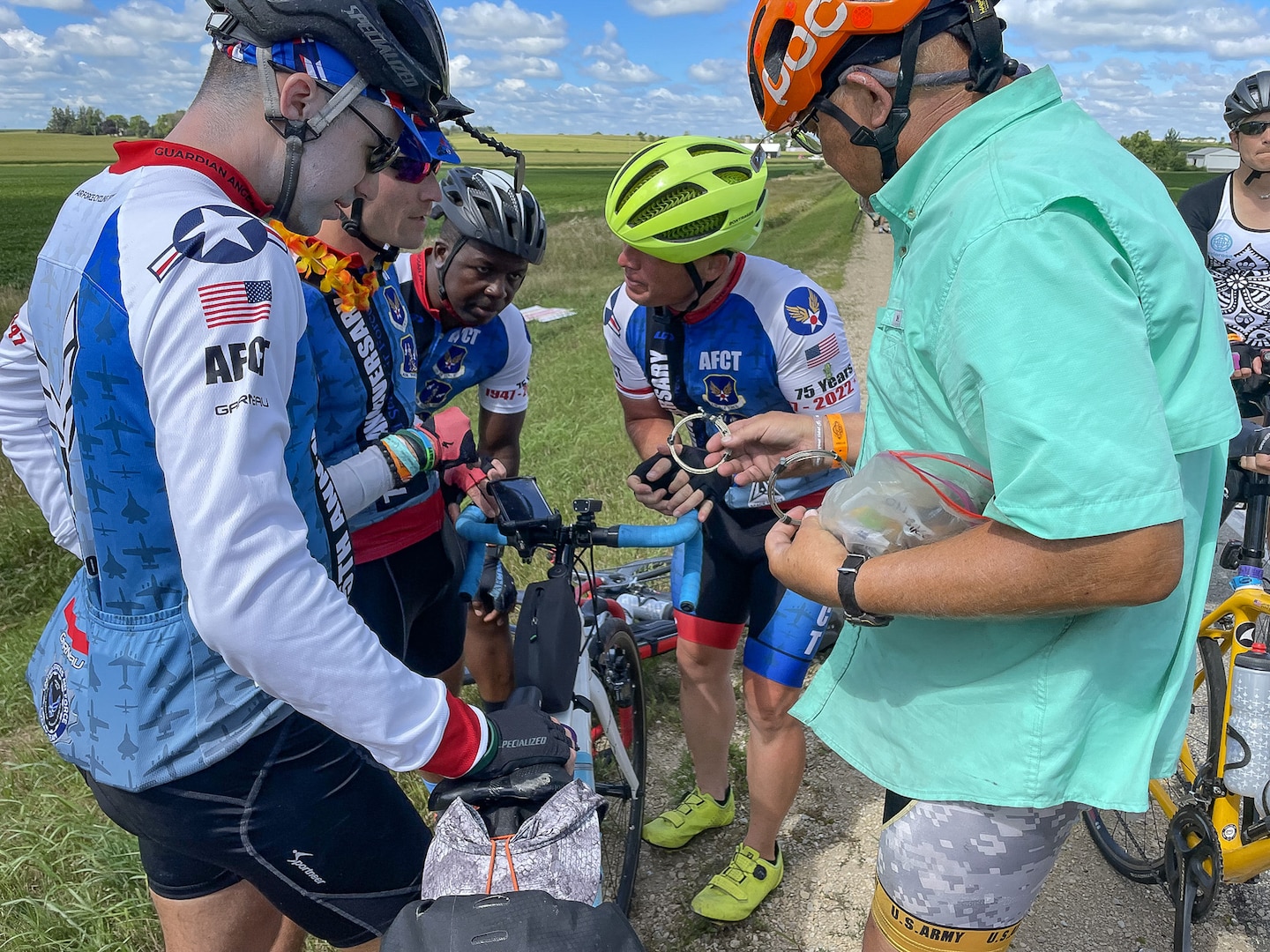 Group of cyclist work on a bicycle next to a roadway.