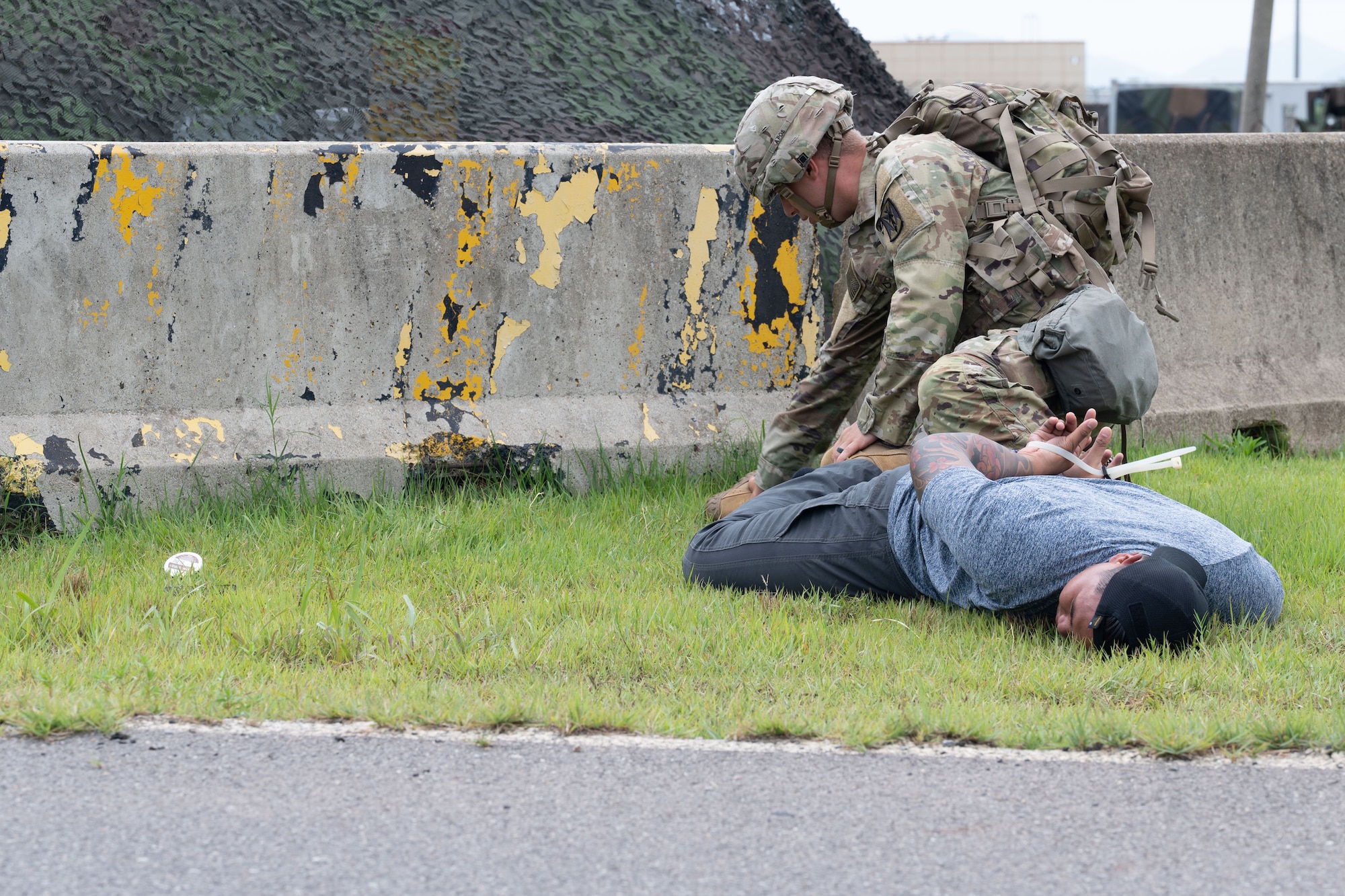An Army solder conducts a mock frisk on an Air Force Airman in a simulated scenario.