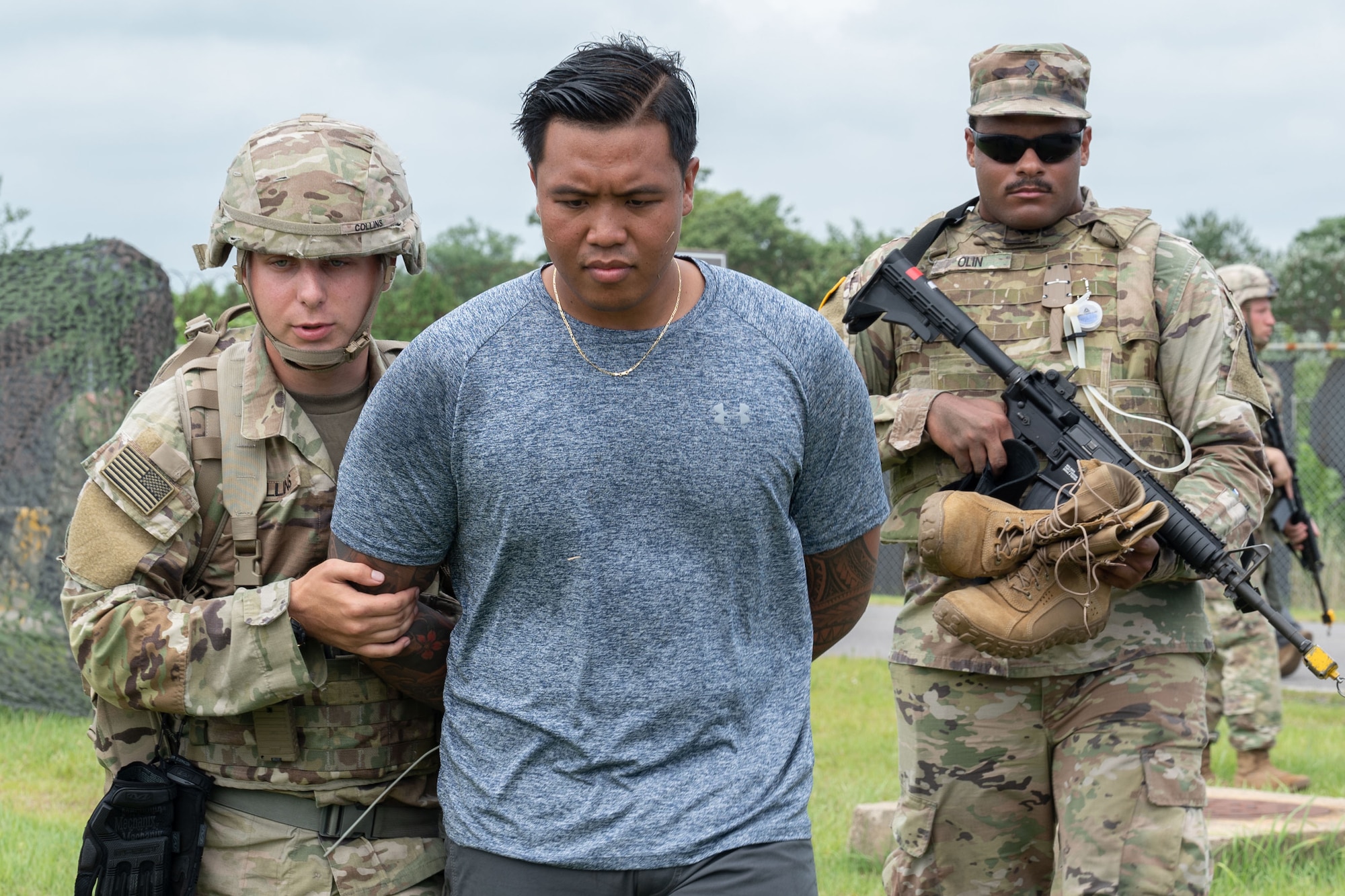 Two Army Soldiers arrest an Air Force Airman in a simulated scenario.