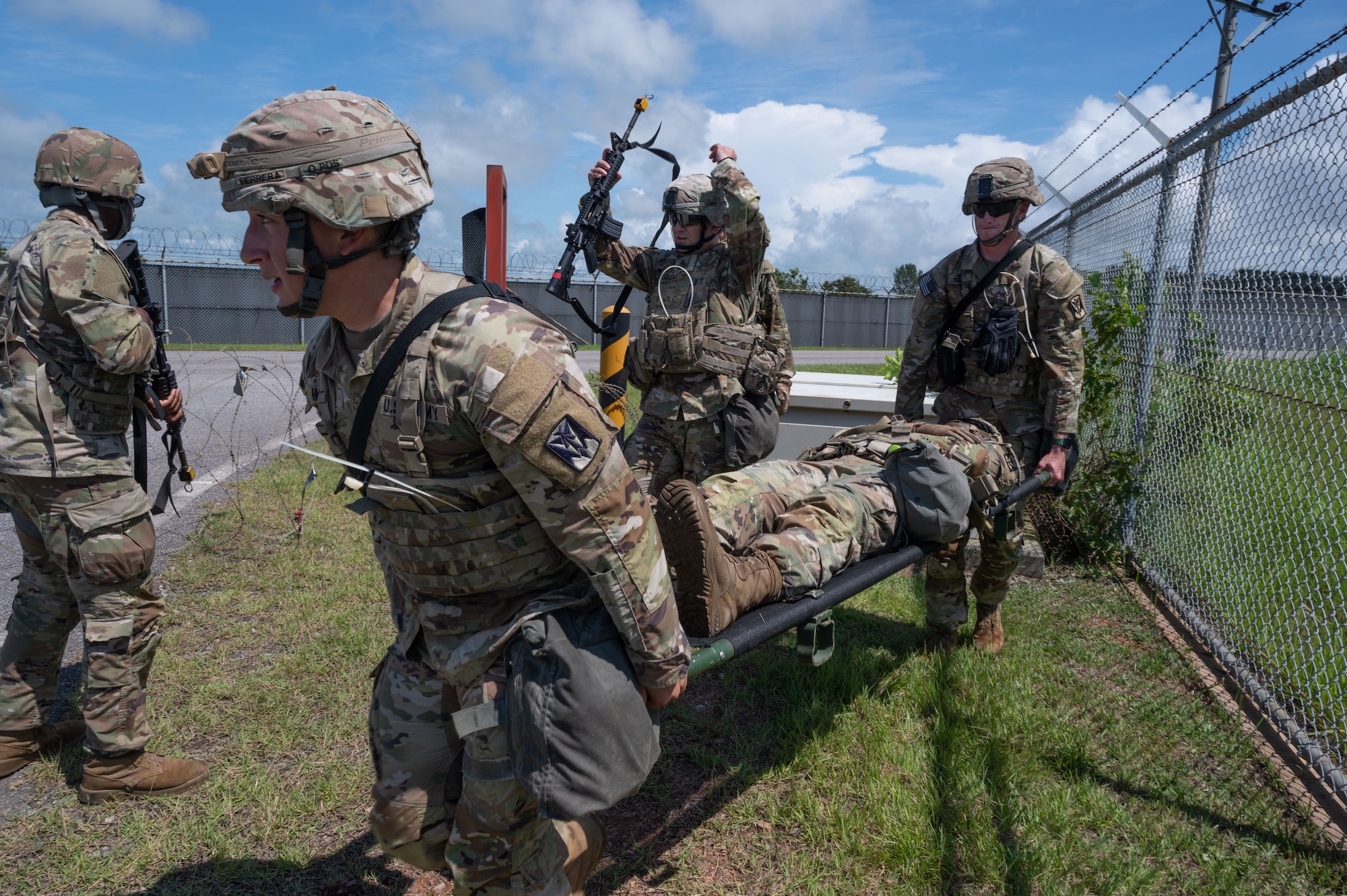 Army Soldiers carry a wounded Soldier in a simulated scenario.