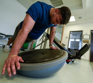 An airman performs pushups with a physical therapy tool indoors.