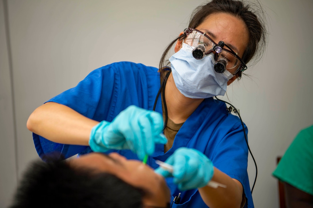 A sailor cleans a patient's teeth.