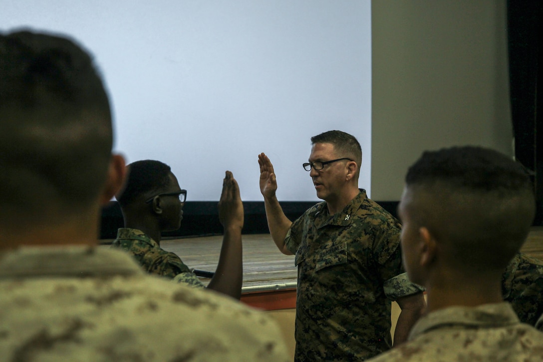 U.S. Marine Corps Cpl. Andrew Ochieng (Left), a supply chain management Marine with 3rd Light Armored Reconnaissance Battalion, 1st Marine Division, recites the oath of enlistment during an Manpower Management Enlisted Assignments Town Hall at Marine Corps Air Ground Combat Center Twentynine Palms, California, Aug. 2, 2022.  At the end of the event, Ochieng, a Richmond, Virginia native, was called to the front and reenlisted on the spot.  (U.S. Marine Corps photo by Cpl. Jonathan Forrest)