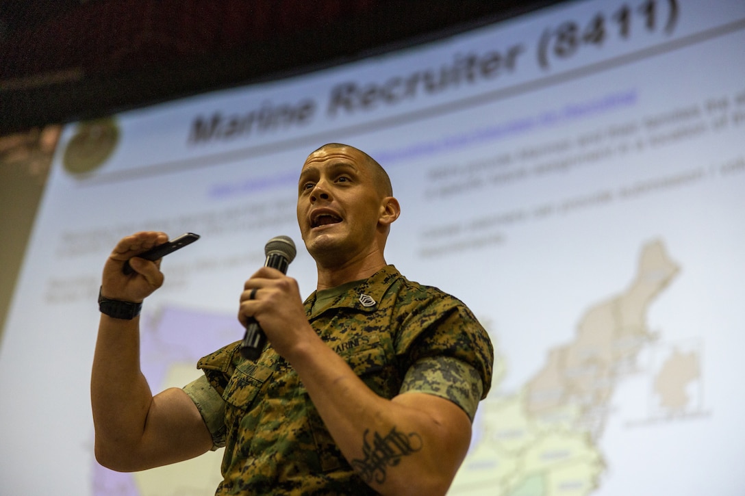 U.S. Marine Corps Gunnery Sgt. Brandon Huad, a drill instructor monitor with Manpower Management Enlisted Assignments (MMEA) 25, speaks to the audience during an MMEA Town Hall at Marine Corps Air Ground Combat Center, Twentynine Palms, California, Aug. 2, 2022.  The purpose of the event was to provide Marines information on the benefits of reenlisting, special duty assignments, and active reserves. n. (U.S. Marine Corps photo by Lance Cpl. Broden Marshall)