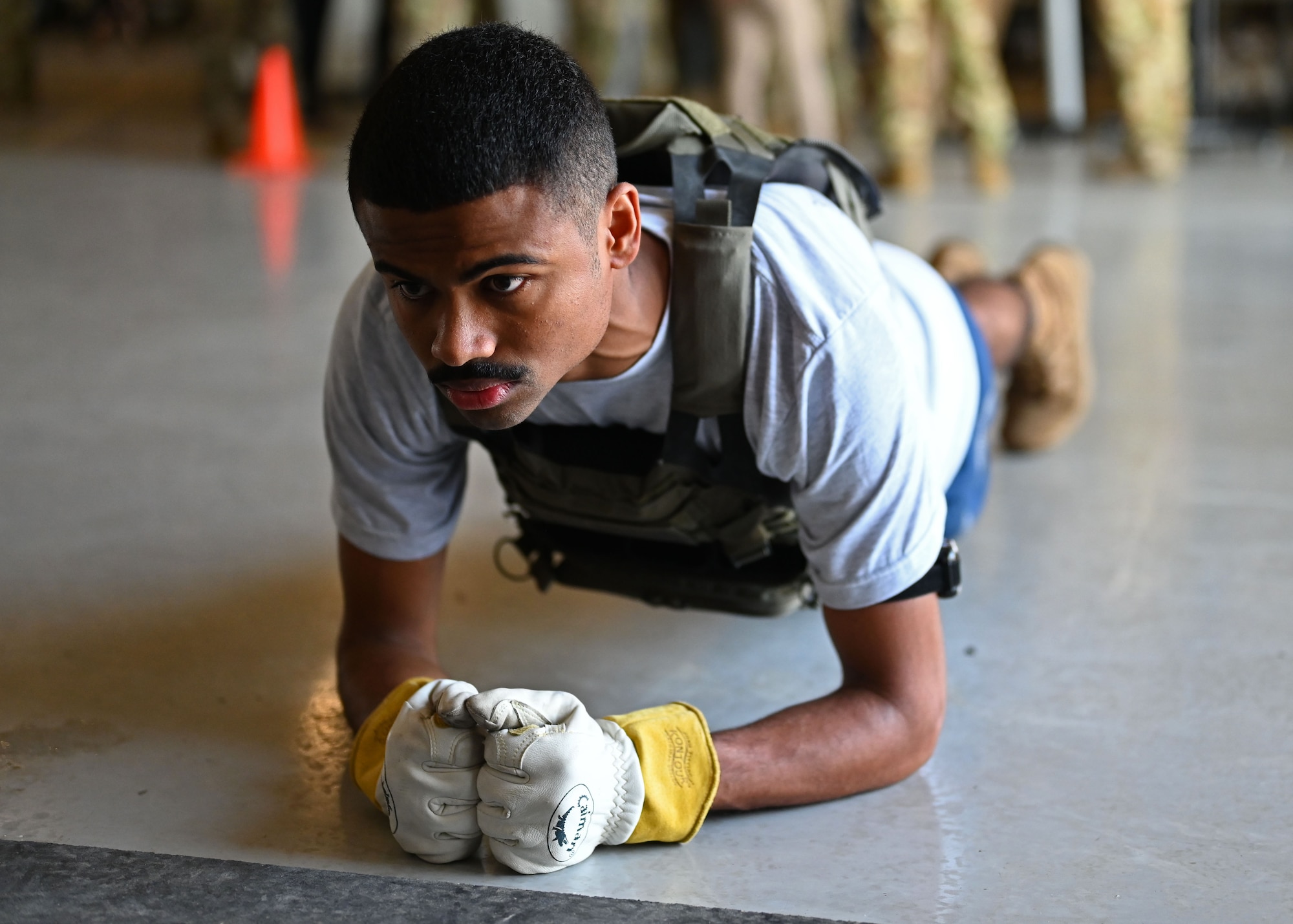 A 312th Training Squadron student maintains a plank position during a Human Performance Integration demonstration for the Air Education and Training Command team as they visited the Louis F. Garland Department of Defense Fire Academy, Goodfellow Air Force Base, Texas, Aug. 11, 2022. The Fire Academy’s student’s physical resiliency is tested to reduce the risk of injuries during training. (U.S. Air Force photo by Senior Airman Ethan Sherwood)
