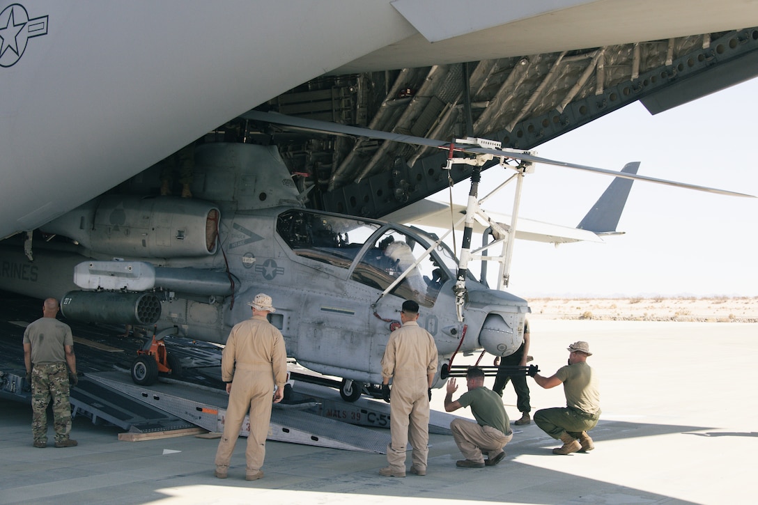 U.S. Marines with Marine Light Attack Helicopter Squadron (HMLA) 267, Marine Aircraft Group 39, 3rd Marine Aircraft Wing, and U.S. Airmen with 3rd Airlift Squadron, 436th Airlift Wing, unload an AH-1Z Viper helicopter from a C-17 Globemaster III aircraft during joint exercise Patriot Hook at Marine Corps Air Ground Combat Center, Twentynine Palms, California, June 29, 2022. Air Force 60th AMW delivered Marine Corps UH-1Y Venom helicopters and AH-1Z Viper helicopters to conduct strike missions, testing HMLA-267 rapid deployment capabilities. (U.S. Marine Corps photo by Lance Cpl. Andrew Bray)