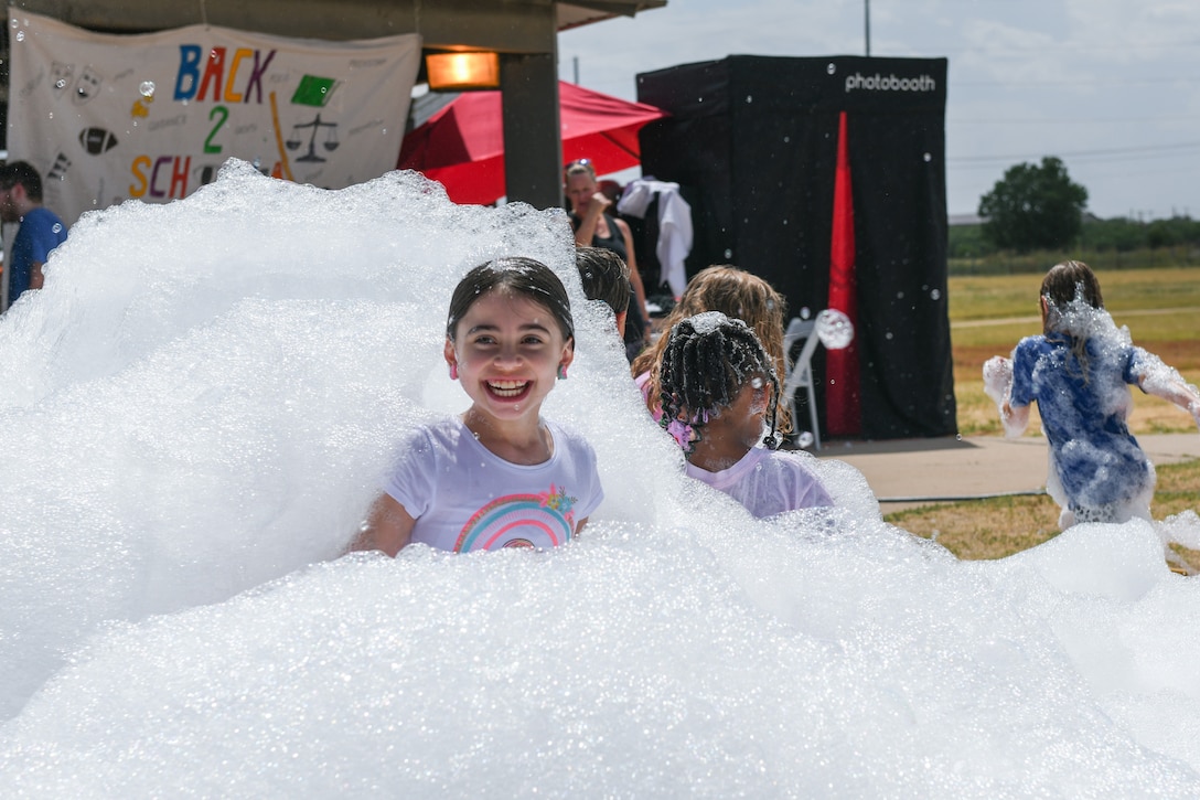 A young girl covered in foam smiles at the camera.