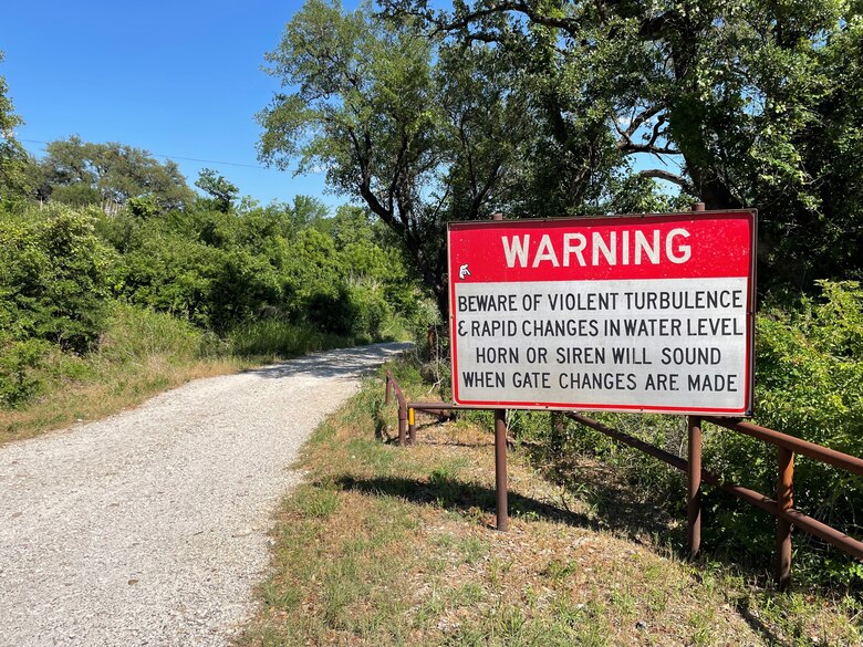 a large warning sign along a roadway with a metal rail barrier