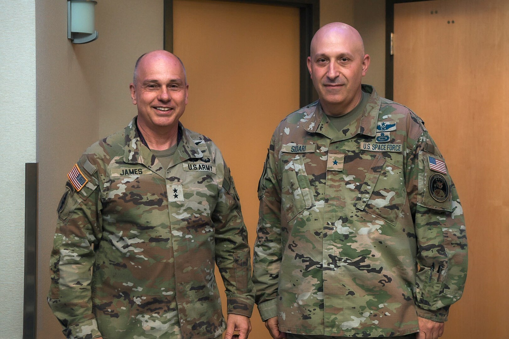 Two men in military uniforms stand next to each other and pose for a photo