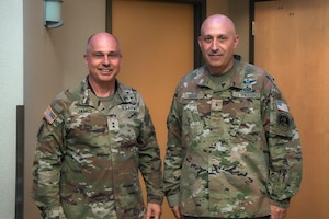 Two men in military uniforms stand next to each other and pose for a photo