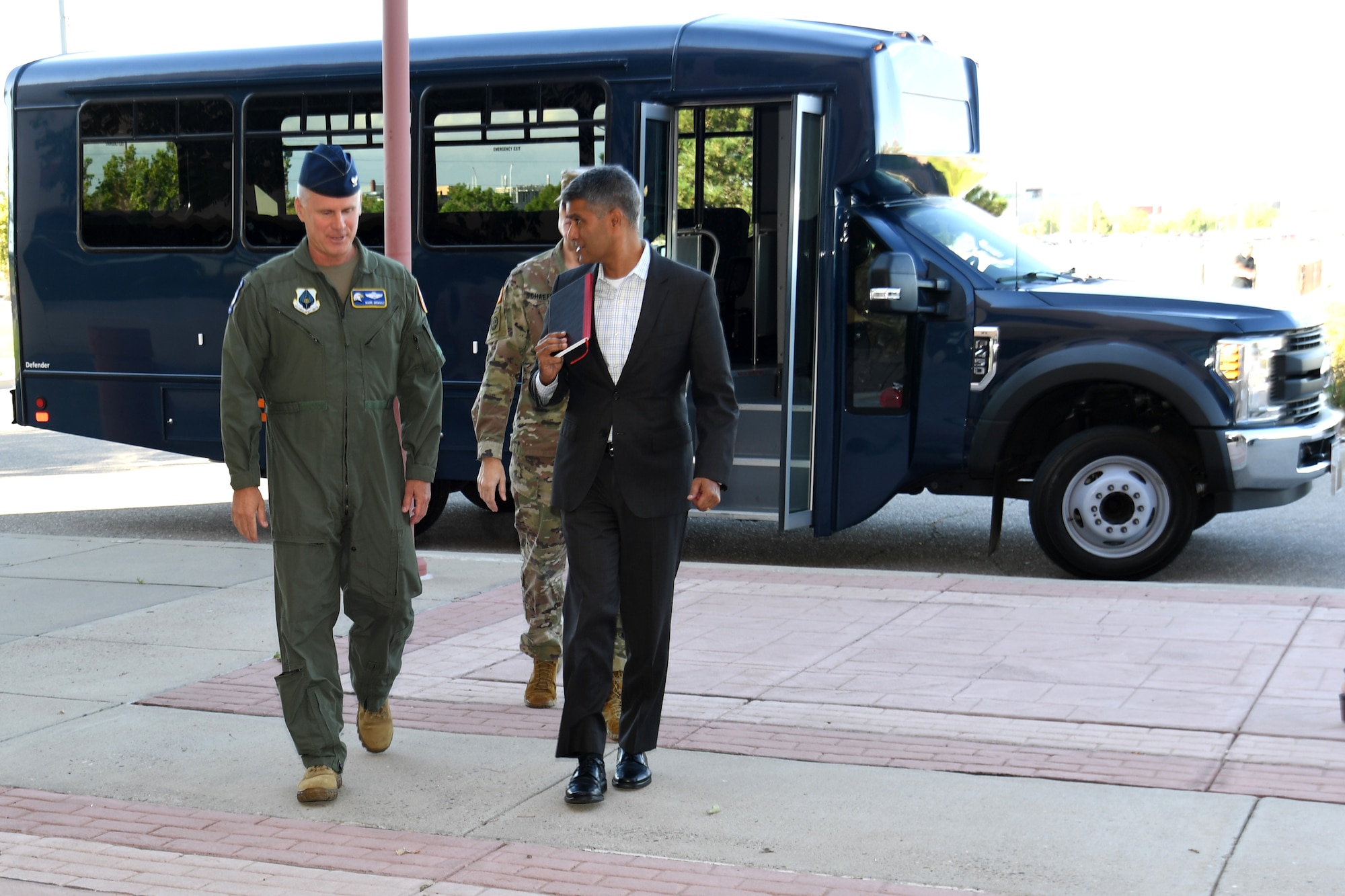 Military and civilian personnel walking into building