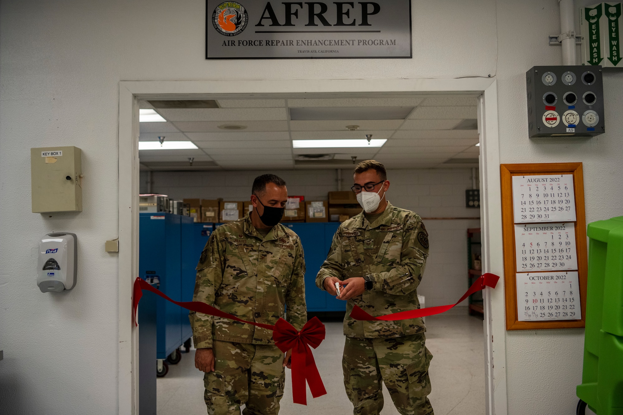 Men in uniform cut a red ribbon in a doorway.