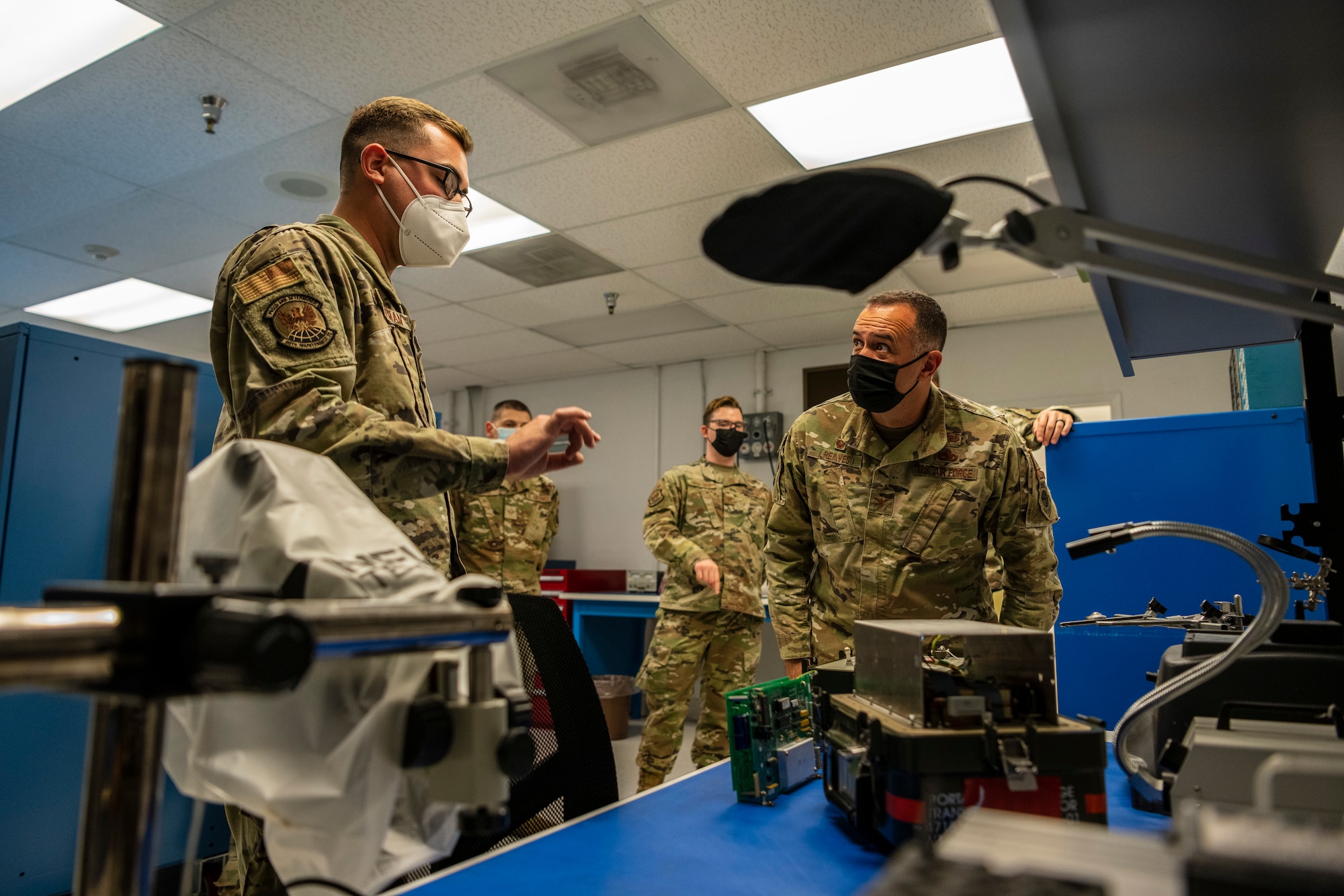 Men in uniform pointing and looking at equipment that can be repaired.