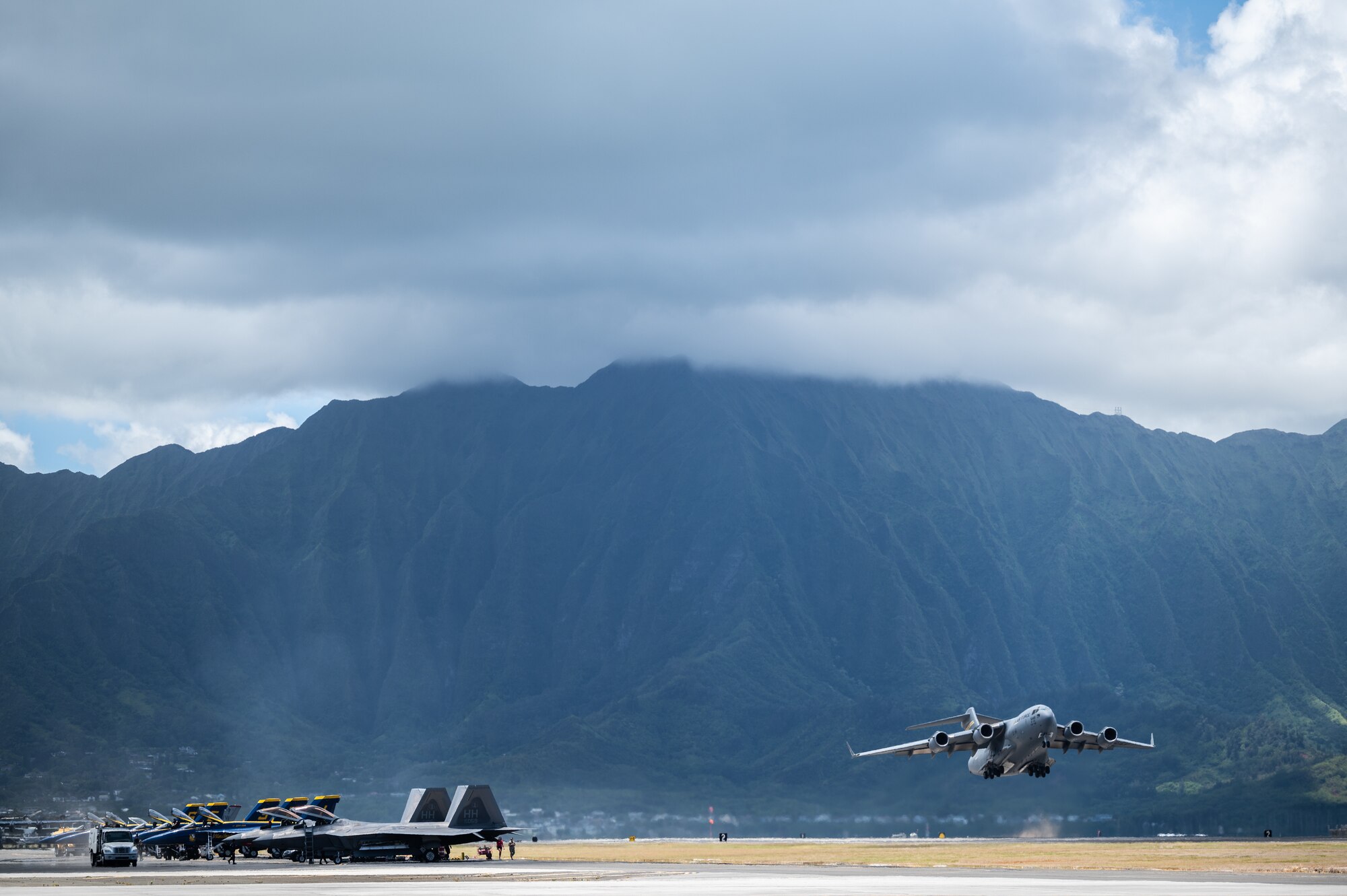 F-18 Hornets assigned to the Blue Angels, a C-17 Globemaster III assigned to the 535th Airlift Squadron and F-22 Raptors assigned to the Hawaii Air National Guard participate in the  Kaneohe Bay Air Show at Marine Corps Base Hawaii, Hawaii, Aug. 12, 2022. The three-day event featured performances by several military aircrews, demonstrating aircraft operations and capabilities. (U.S. Air Force photo by Staff Sgt. Alan Ricker)