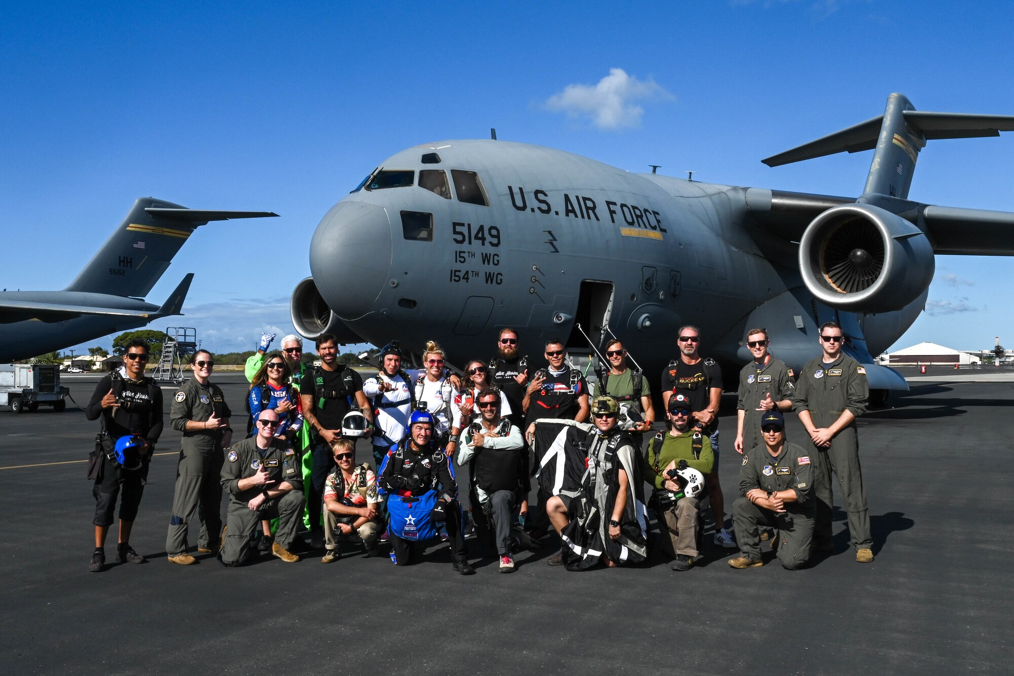 Airmen assigned to the 535th Airlift Squadron pose for a photo with members from the Flying Leathernecks Demonstration Skydiving team before the Kaneohe Bay Air Show at Joint Base Pearl Harbor-Hickam, Hawaii, Aug. 13, 2022. The airshow kicked off with an aerial performance by 16 members of the team. (U.S. Air Force photo by Senior Airman Makensie Cooper)