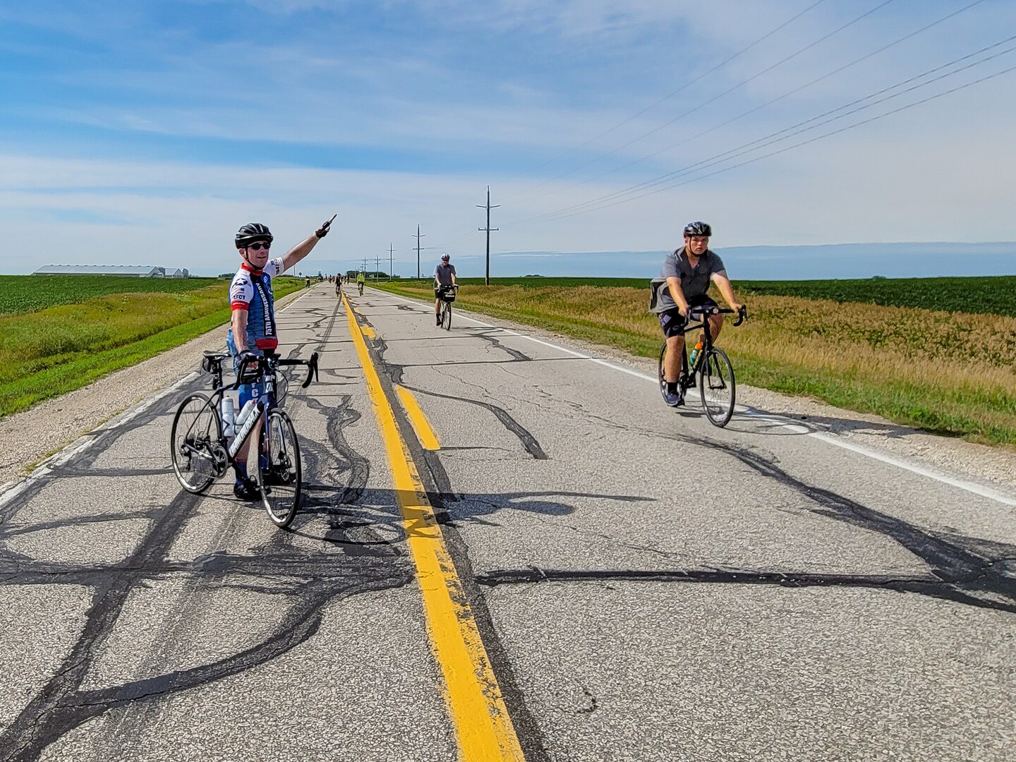 A cyclist standing in the road waves bike traffic to the right.