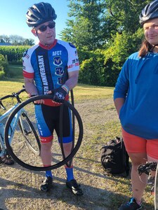 Two cyclist standing with one holding an inner tube