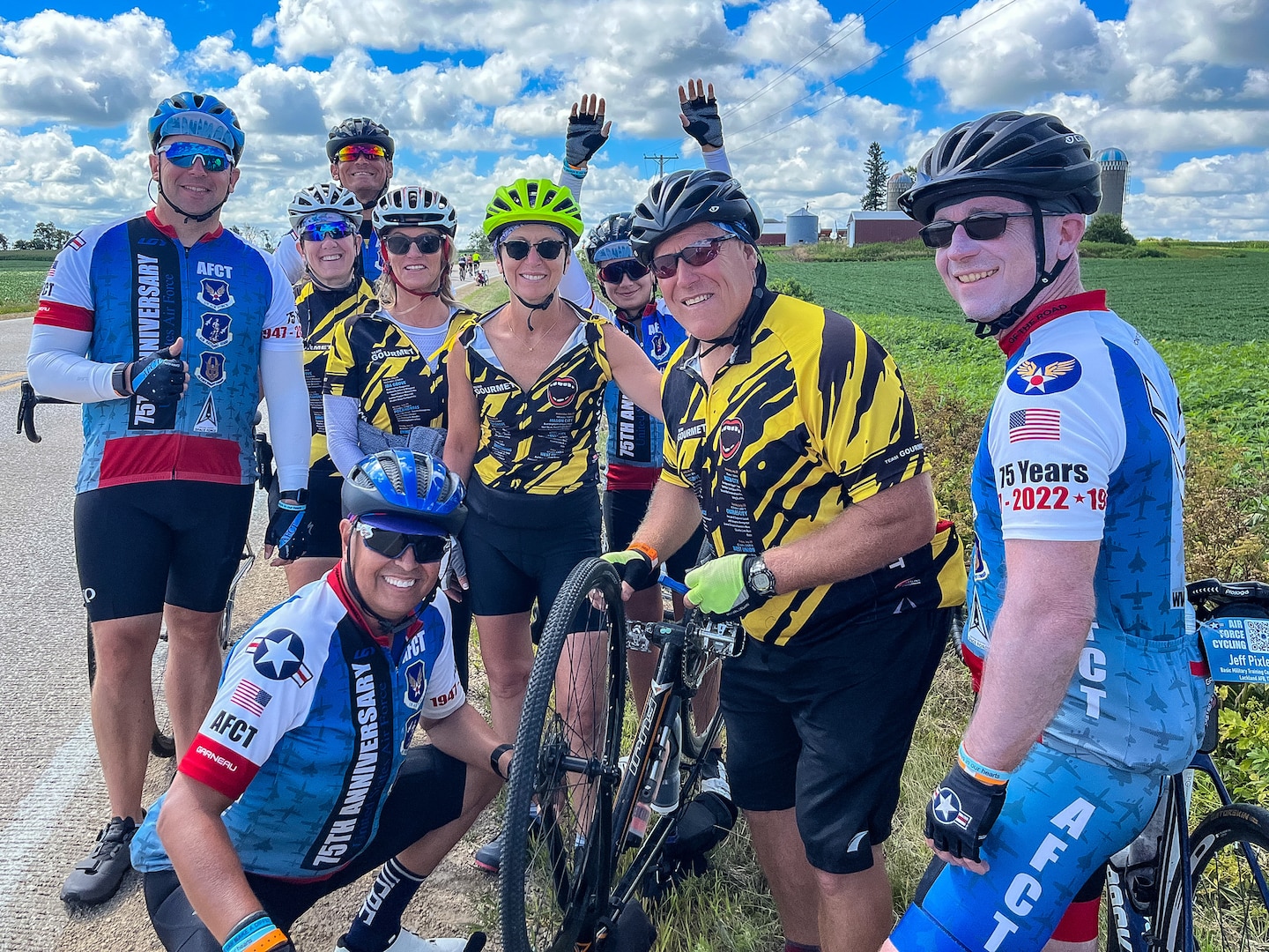 group of cyclist pose for a photo on the side of the road