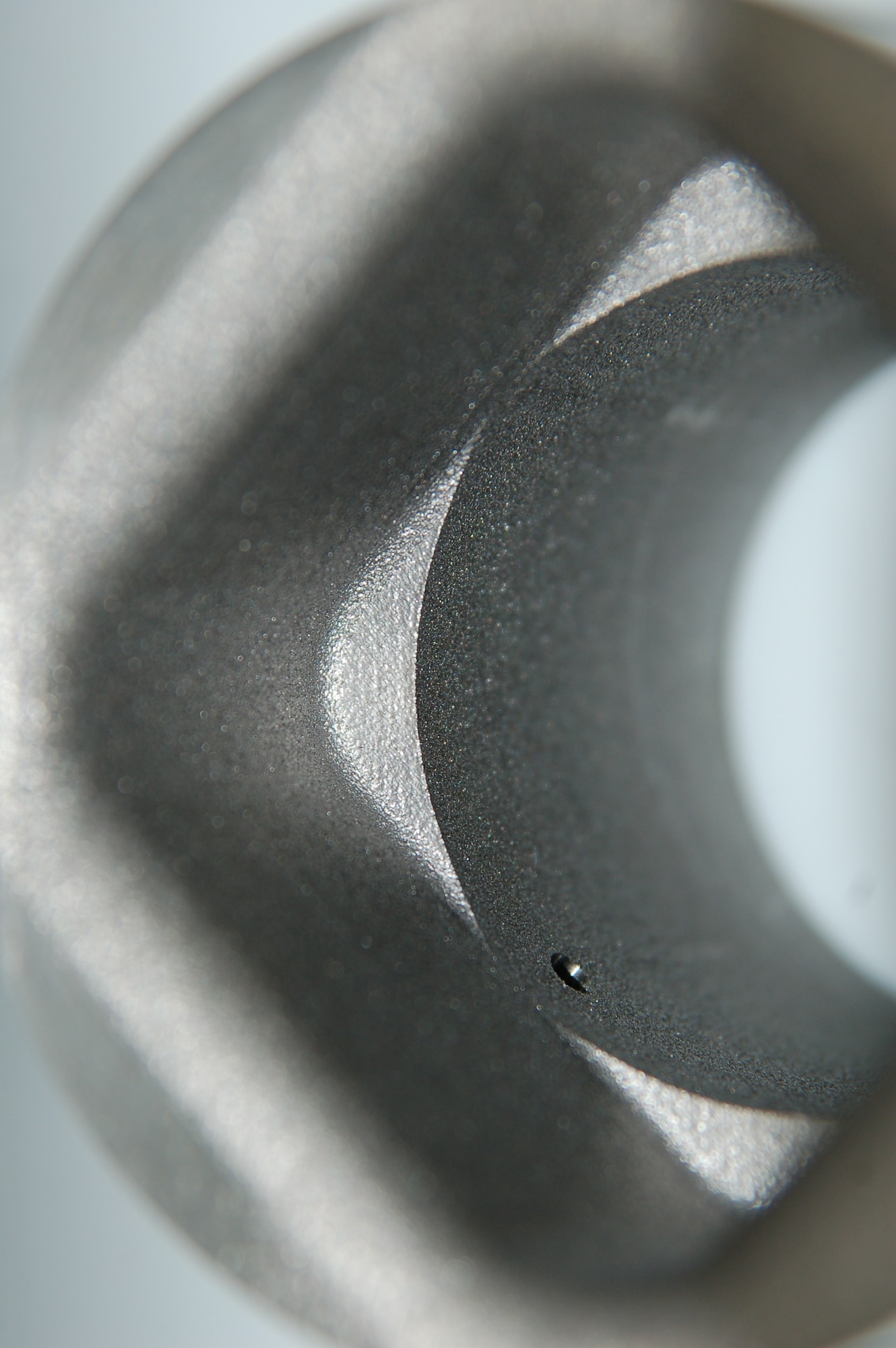 Pictured is an up-close view of a petal orifice liner created at Arnold Engineering Development Complex Hypervelocity Wind Tunnel 9 in White Oak, Maryland, using additive manufacturing, otherwise known as 3D printing. The liner is integral to high Mach number tunnel runs at Tunnel 9 and can experience temperatures of several thousand degrees. The refractive metal part has an outside diameter of around 3 inches, an inside diameter of around 2 inches and is nominally 3 inches in length. Additive manufacturing machines at Tunnel 9 are also capable of much larger prints, in the ballpark of 18 to 24 inches in any direction. (U.S. Air Force photo)