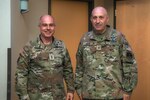 Two men in military uniforms stand next to each other and pose for a photo