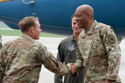 Two men in military uniforms shake hands.