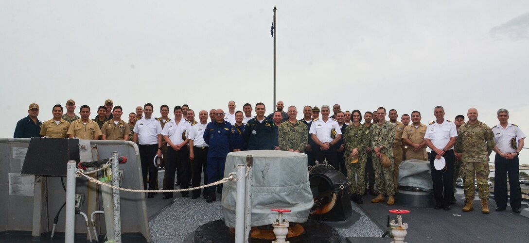 U.S. and partner nation participants from the Combined Force Maritime Component Command pose for a group photo on the fantail of the guided-missile destroyer USS Thomas Hudner (DDG 116) during a ship tour, following the completion of PANAMAX 2022, Aug. 11, 2022. Exercise PANAMAX 2022 is a U.S. Southern Command-sponsored exercise that provides important training opportunities for nations to work together and build upon the capability to plan and conduct complex multinational operations. The exercise scenario involves security and stability operations to ensure free flow of commerce through the Panama Canal.
