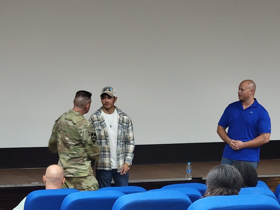 U.S. Air Force Staff Sgt. Devin Flores accepts a challenge coin at an undisclosed location, July 23, 2022. He was coined in recognition of his contributions to the DOD Men's SAPR campaign, which trained and educated attendees to help male survivors of sexual assault. (Courtesy Asset)