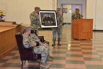 Col. Patrick Monahan, outgoing fommander of the 166th Regiment Regional Training Institute, presents a framed print to the schoolhouse during a change-of-command ceremony on Aug. 12, 2022, at Fort Indiantown Gap, Pa. (Pennsylvania National Guard photo by Brad Rhen)
