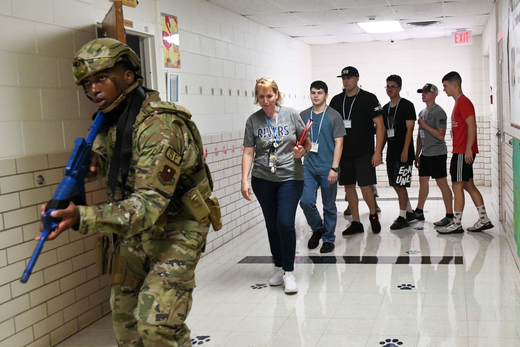 A defender from the 97th Security Forces Squadron escorts “victims” to safety during an active shooter training exercise at Altus Air Force Base, Oklahoma, Aug. 10, 2022. During the exercise, defenders cleared all rooms in the school and led everyone to safety. (U.S. Air Force photo by Airman 1st Class Miyah Gray)