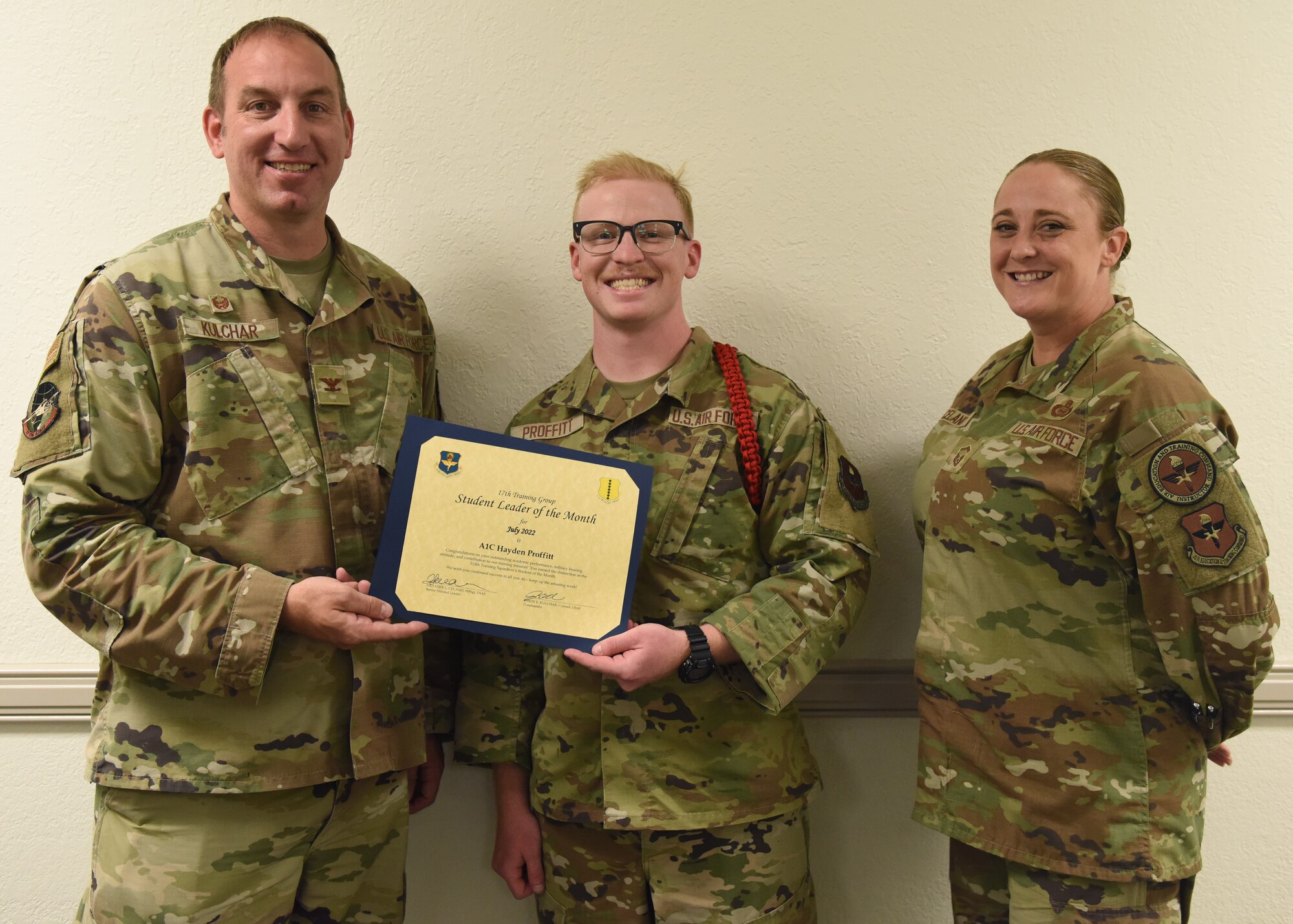 U.S. Air Force Col. Jason Kulchar, 17th Training Group commander, and Senior Master Sgt. Heather Celano, 313th Training Squadron senior enlisted leader, present the 315th Training Squadron Student Leader of the Month award to Airman 1st Class Hayden Proffitt, 315th TRS student, at Goodfellow Air Force Base, Texas, August 12, 2022. Proffitt worked hard for his award and has shown his dedication to his squadron and the training he received at Goodfellow. (U.S. Air Force photo by Airman 1st Class Zachary Heimbuch)