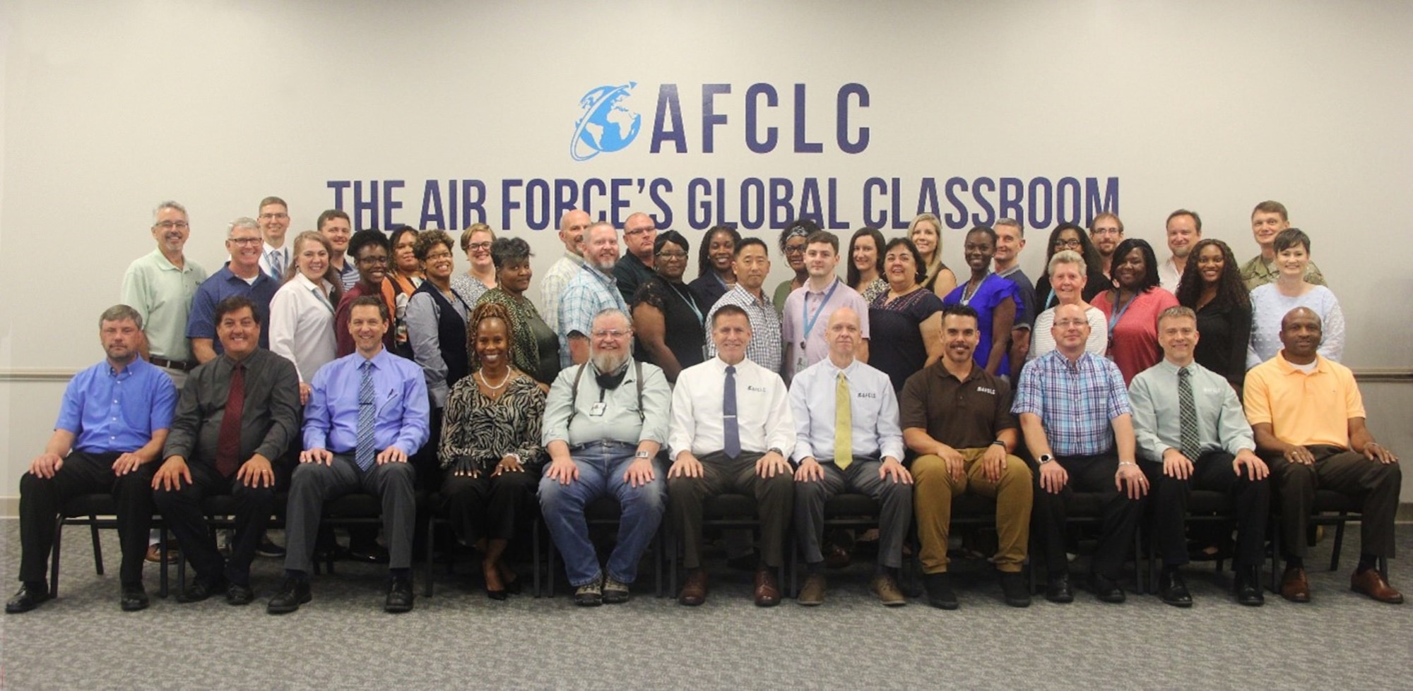 AFCLC staff members in class picture format in front of AFCLC banner