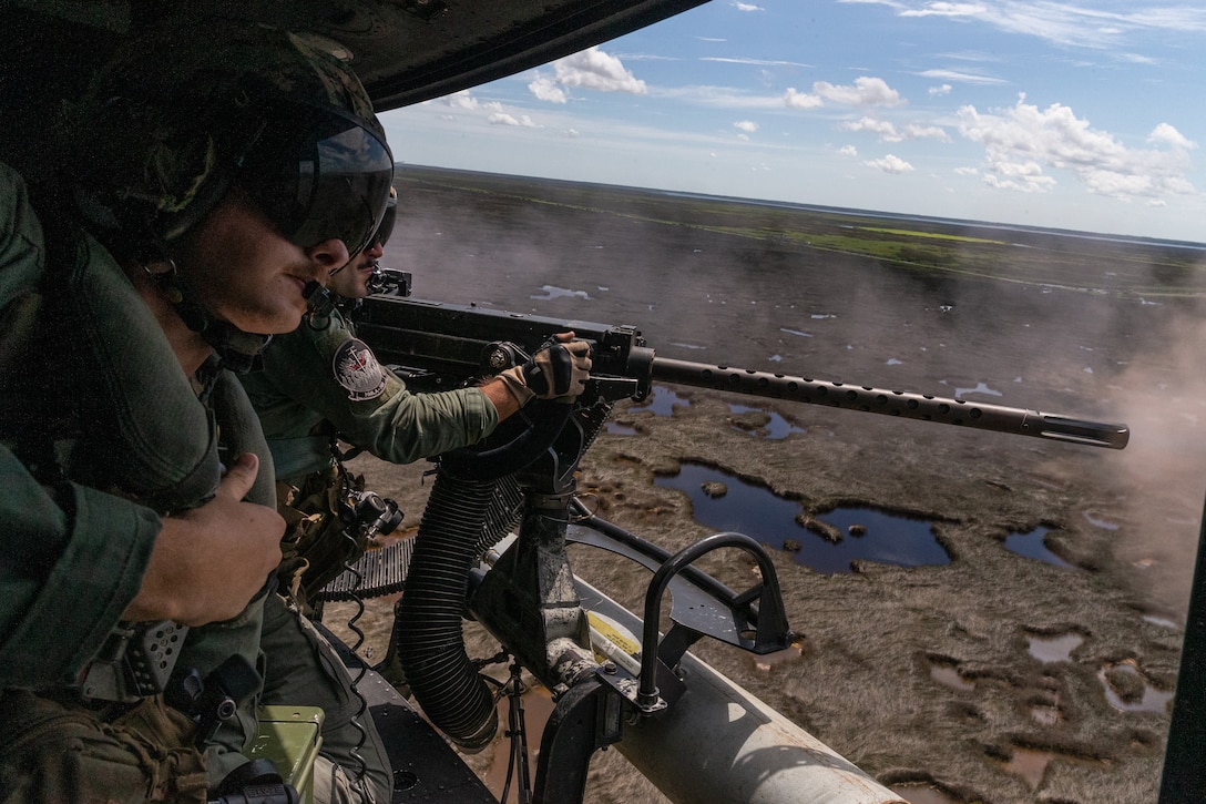 U.S. Marine Corps Cpl. Liam A. Hogan (right), a UH-1Y Venom crew chief with Marine Light Attack Helicopter Squadron (HMLA) 269, fires a GAU-21 .50-caliber machine gun near Marine Corps Air Station New River, North Carolina, Aug. 9, 2022. HMLA-269 trained to increase proficiency in close-air support. HMLA-269 is a subordinate unit of 2nd Marine Aircraft Wing, the aviation combat element of II Marine Expeditionary Force. (U.S. Marine Corps photo by Lance Cpl. Anakin Smith)